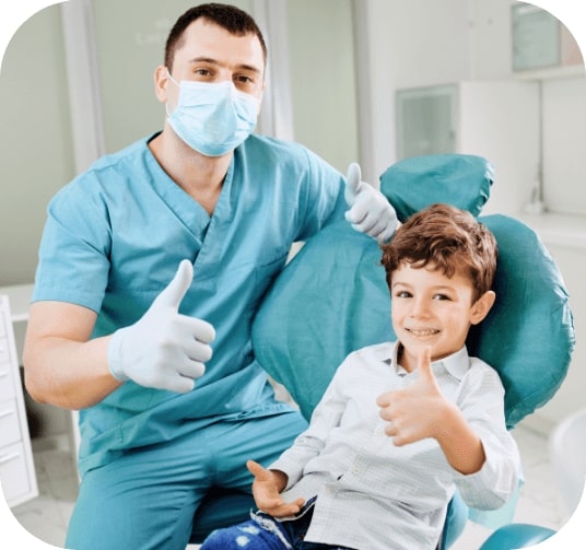Dentist and child in dental office giving thumbs up