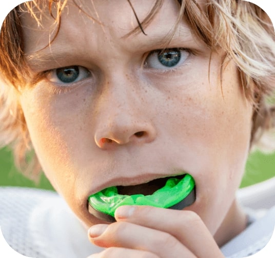 Young athlete placing an athletic mouthguard