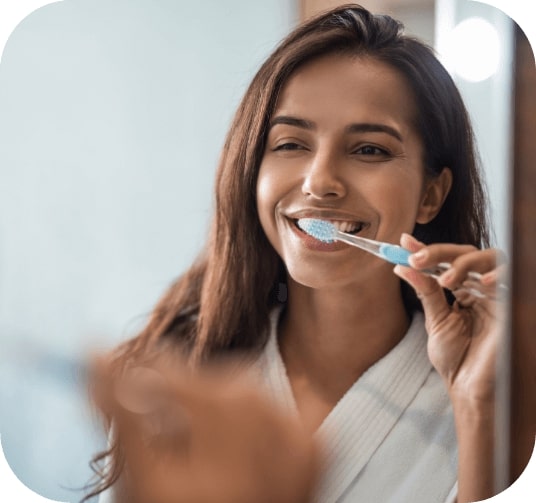 Woman brushing teeth to prevent dental emergencies