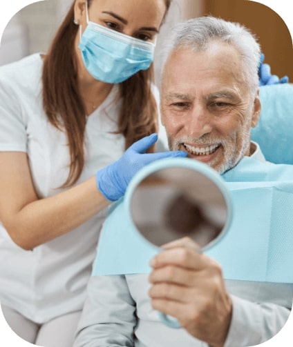 Man looking at smile after tooth replacement with dental implants