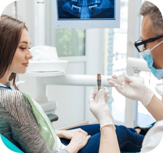 Dentist using smile model to explain the four step dental implant process