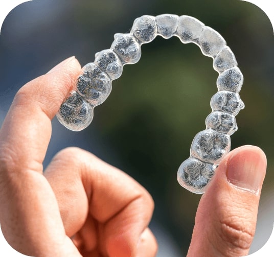 Hand holding an Invisalign orthodontics tray